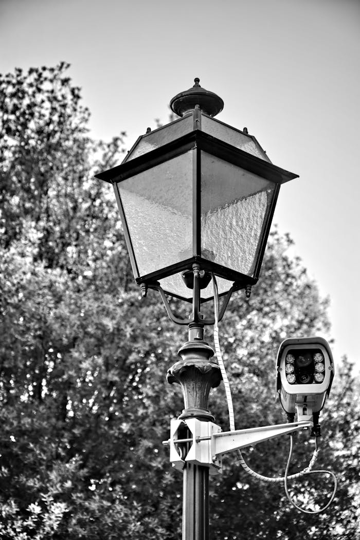 Vintage street lamp and CCTV camera in monochrome, capturing urban security.