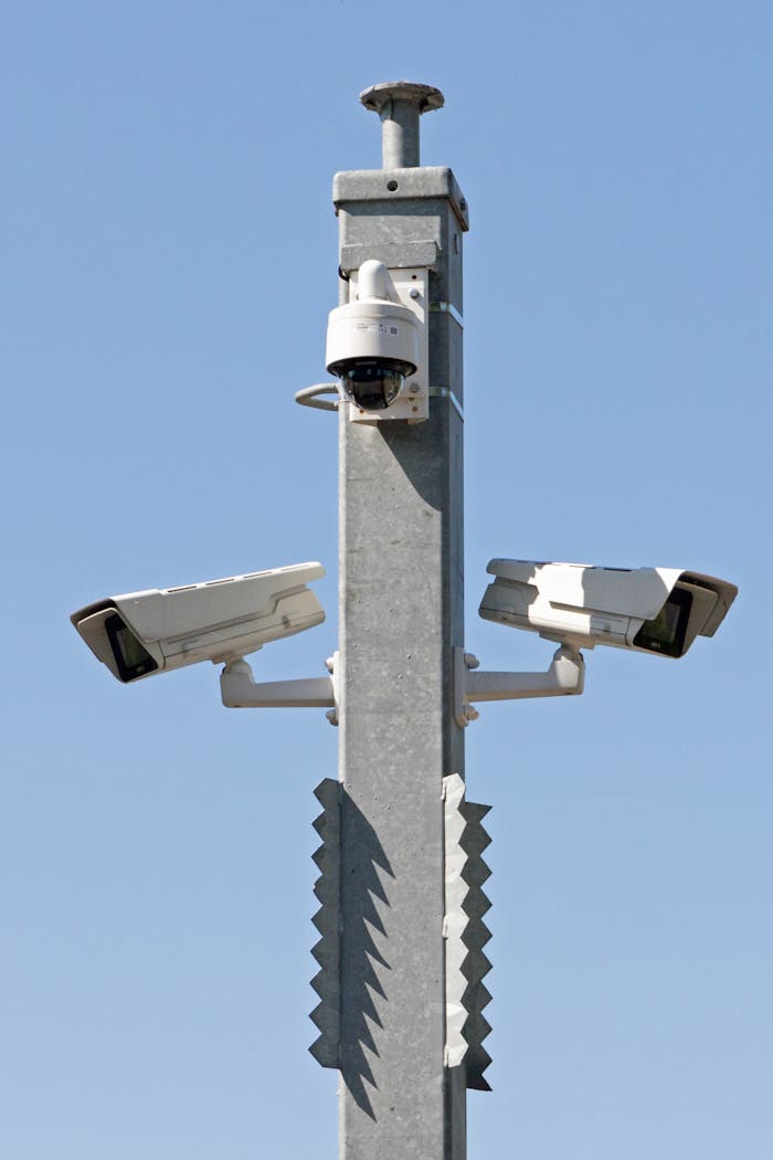 Outdoor surveillance system with multiple cameras mounted on a metal pole against blue sky.